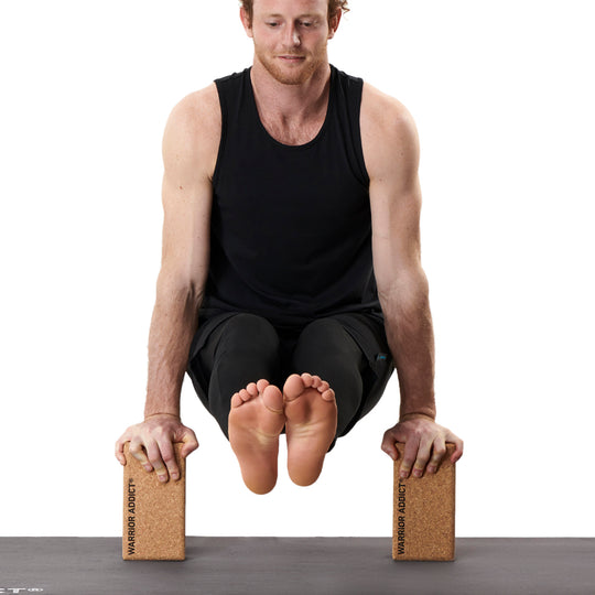 man doing arm balance with two cork yoga blocks on yoga mat 