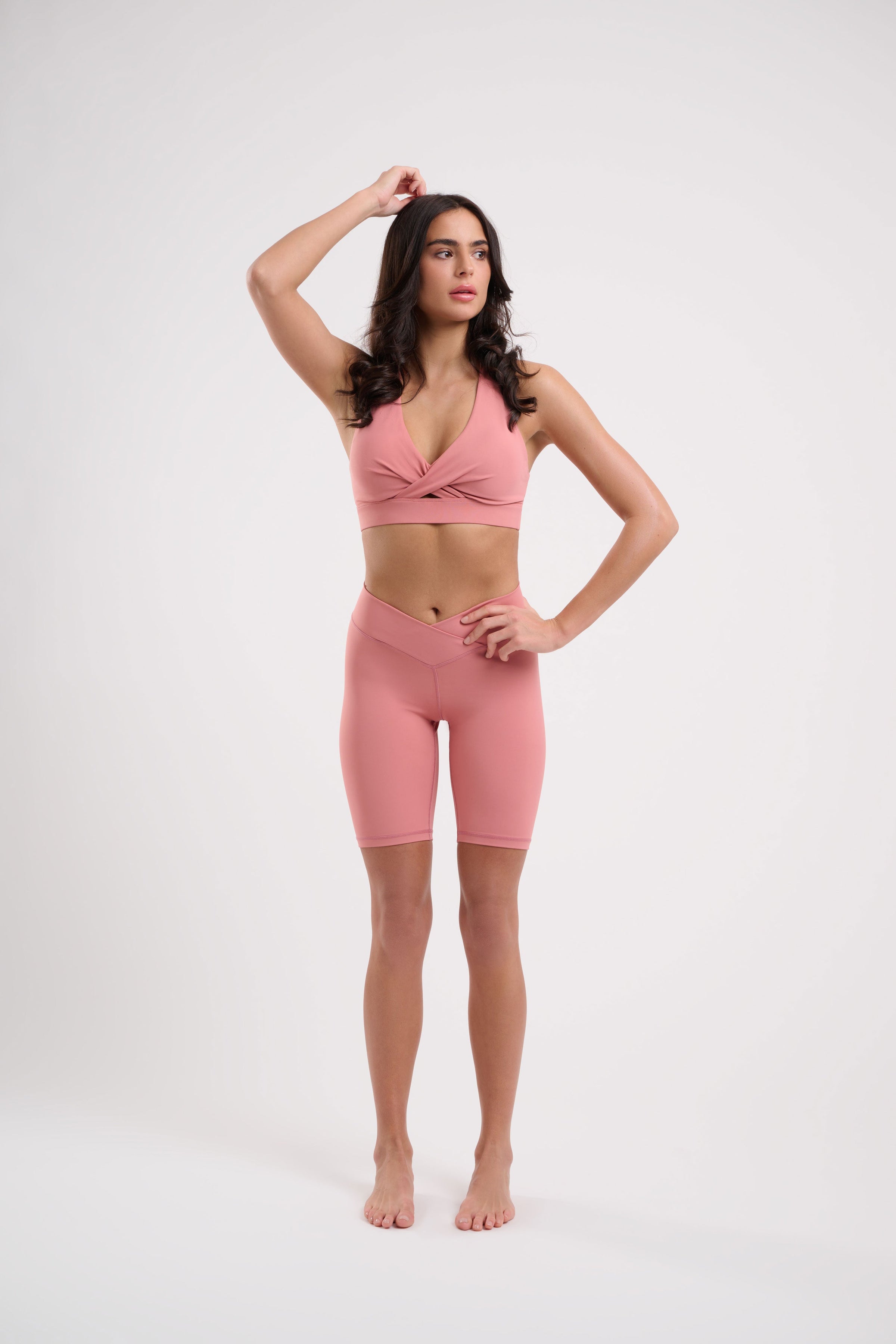 Woman in pink athletic wear, hand on head.